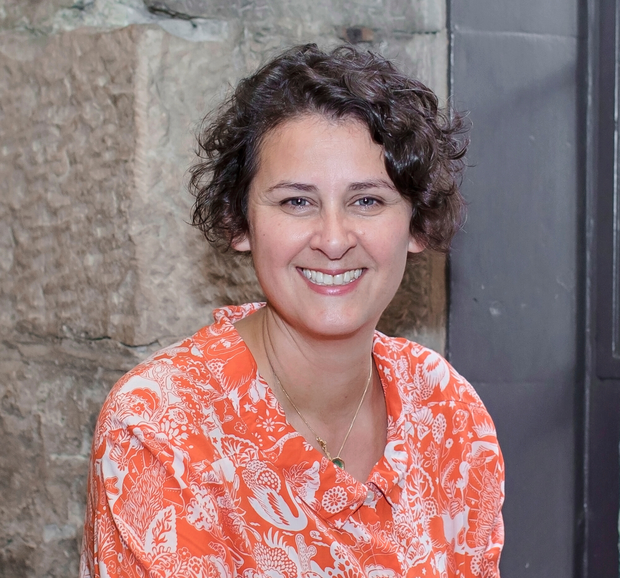 Photo of a woman with dark hair wearing an orange blouse