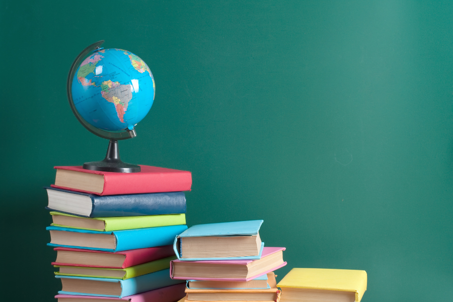 A stack of books with a world globe on top of them