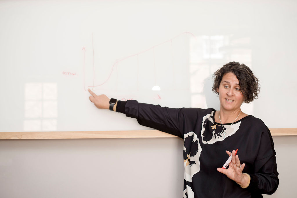 Emma Dhesi teaching a workshop at a whiteboard